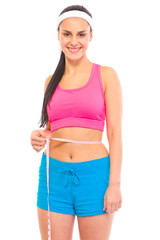 Smiling young girl with perfect sporty body measuring waist