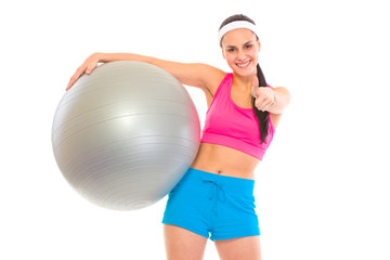 Smiling fit young girl with fitness ball showing thumbs up