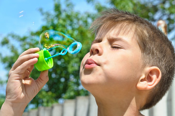 A little boy blows bubbles