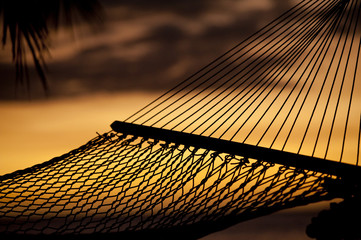 silouhette of hammock on beach overlooking ocean at sunset