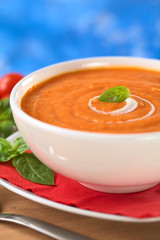 Cream of tomato with spiral of cream and a basil leaf