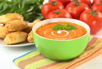 Cream of tomato with spiral of cream and basil leafs