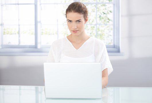 Young woman working on laptop at home smiling