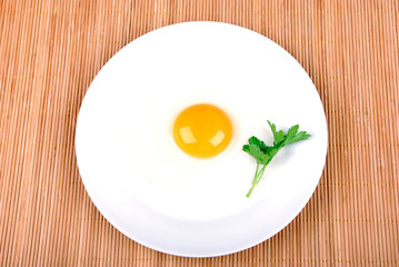 Raw egg broken into white plate, green stalk