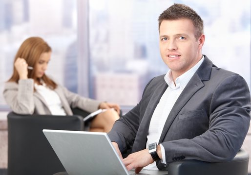 Middle-aged businessman using laptop in hall