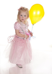 Fototapeta na wymiar little girl in pink princess dress holding yellow balloon