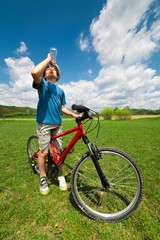 Boy on a bicycle drinking water