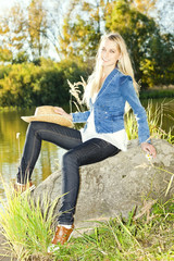 young woman sitting on stone at pond