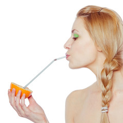 woman drinking juice direct from an orange fruit using a straw