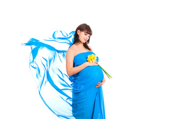 pregnant woman holding flower сovered with blue satin fabric