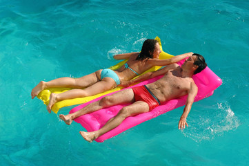 Happy young woman and the man in water pool