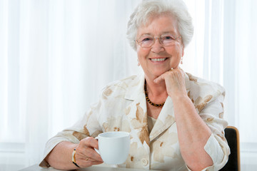 Beautiful senior woman enjoying a cup of tea or coffee