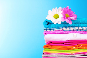 Pile of colorful clothes and flowers   on blue background
