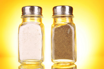 Glass salt and pepper shakers  on yellow background