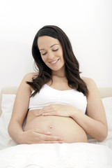 Pregnant woman looking at her growing tummy