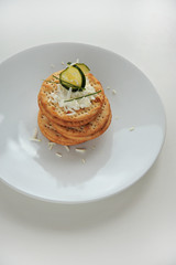 Pile of round crackers with cheese and cucumber