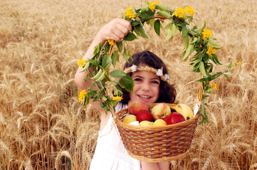Girl Holds Basket of Fruit in Field of Wheat