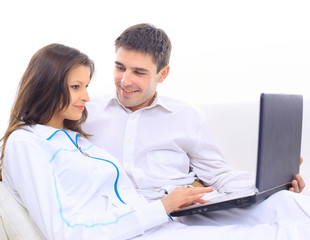 Young couple looking at laptop on sofa