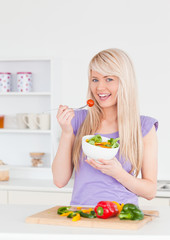 Obraz na płótnie Canvas Blonde smiling woman eating her salad