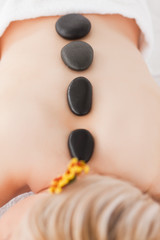 Obraz na płótnie Canvas Blonde woman relaxing with hot stones on her back