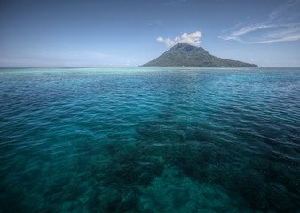 Coral reef transparent sea and white clouds. Bunaken island. Indonesia