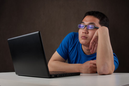 bored and tired young asian man working with his computer