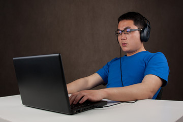 young asian man playing games on laptop computer