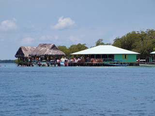 Over the water tropical bar restaurant with tourist and boat, Coral cay, Bocas del Toro, Panama, Central America