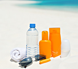 water and sun protection cream on beach background