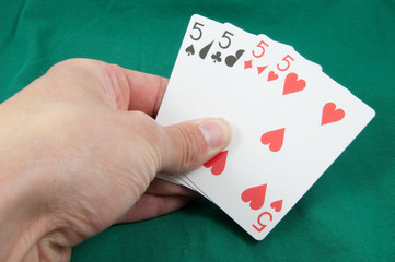 four fives in card hand on green card table
