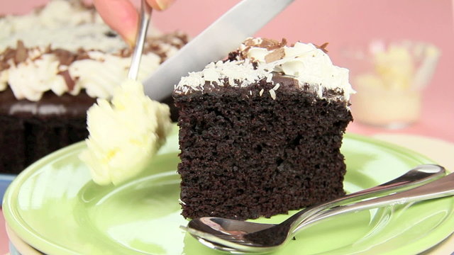 A slice of mud cake garnished with cream and white chocolate.