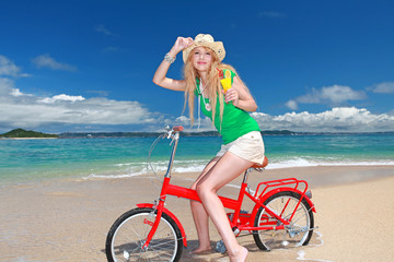 Obraz na płótnie Canvas 波打ち際で自転車に乗っている笑顔の女性