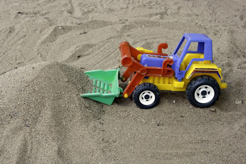 Sand and toy tractor car.s
