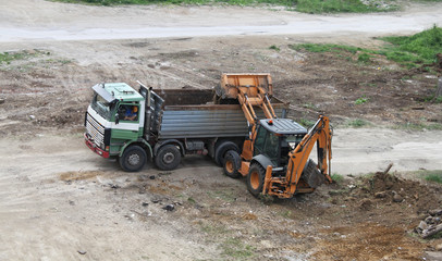 Excavator loading dirt on truck. Construction equipment at work