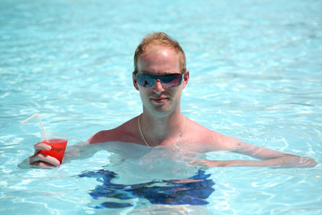 Porträt eines jungen Mannes in den Pool mit einem Cocktail