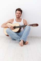 Sexy guitarist sitting on floor smiling