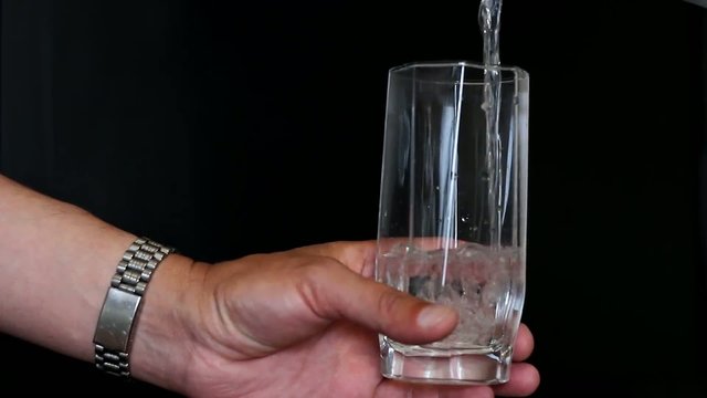 water flowing to the glass holding a hand