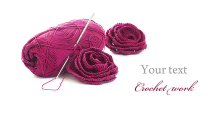 Crochet work: skein of yarn, crochet hook and crocheted roses
