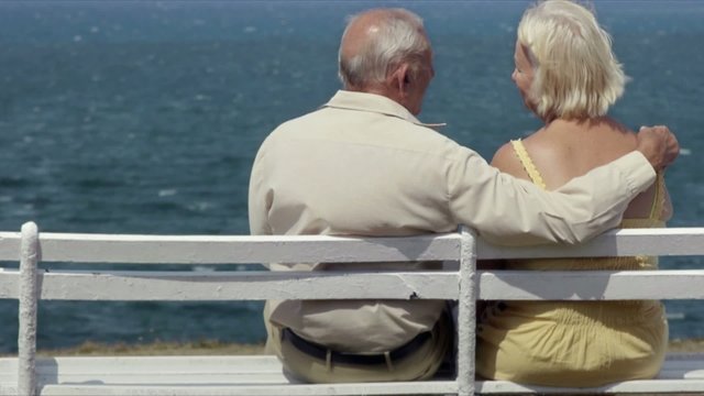 old man and woman on bench at the sea