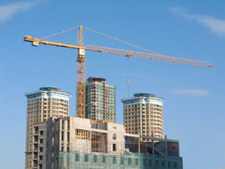 Fototapeta na wymiar Yellow hoisting crane and some constructing buildings