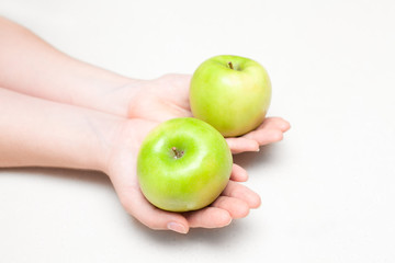 Two green apples in female hands on white background