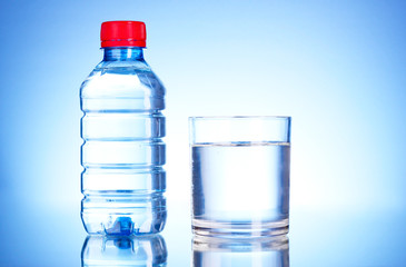 Naklejka premium Bottle of water and glass on blue background