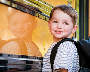 Young boy with nervous smile waits to board school bus