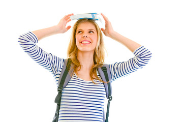 Cheerful girl balancing book on top of head isolated on white .