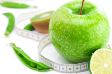 apple,lime,peas,kiwi and measure tape isolated on white