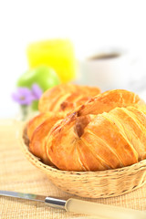 Fresh croissants in bread basket with coffee and orange juice