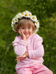 little girl in camomile diadem is siting supported by hand