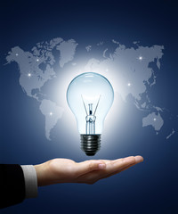 Light bulb in hand businessman on world map blue background.