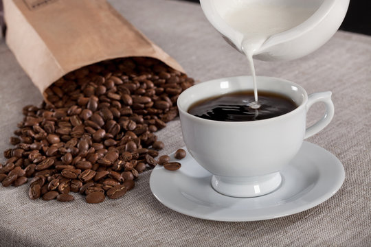 Milk pouring into a cup of coffee