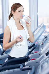 Young woman at the gym exercising. Drink